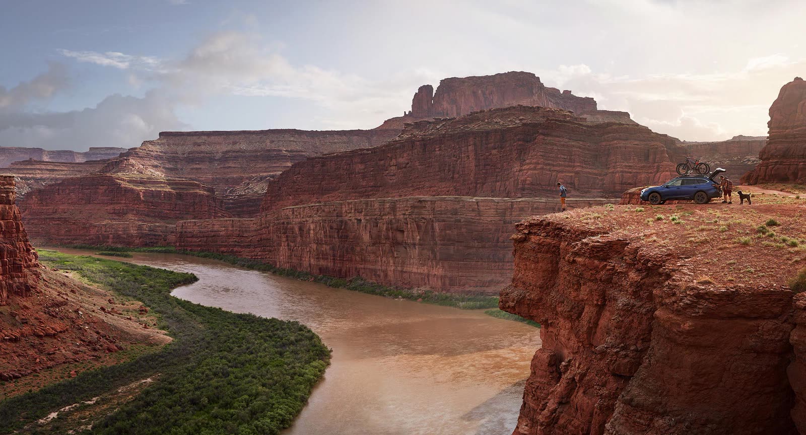 A canyon river bend at dusk, a car parked on the cliff edge
